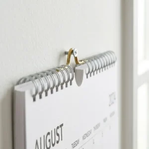 Close-up of the sturdy twin-wire binding and hanging hook of a professional academic year wall calendar.