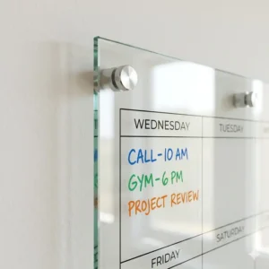 Close-up of the premium glass surface of a weekly planner board for wall with stainless steel mounts.
