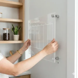 Hands holding a weekly planner board for wall to demonstrate the easy installation process.