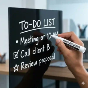 A hand writing a "To-Do" list using a bold white dry erase marker on a black glass board.