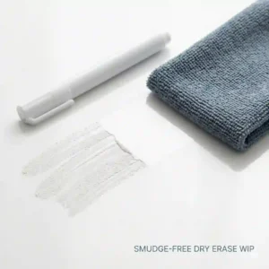 A microfiber cloth easily erasing white dry erase marker ink from a non-porous surface without ghosting.