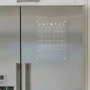 Clear acrylic magnetic calendar for refrigerator doors mounted on sleek stainless steel."